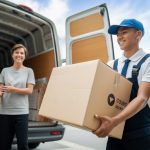 A courier handing over a large parcel to a smiling customer outside a delivery van in a city setting.