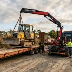 Hiab lifting a bulldozer onto a flatbed trailer