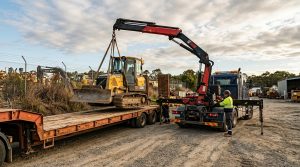 Hiab lifting a bulldozer onto a flatbed trailer